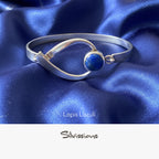 Silver bangle with a blue gemstone on a neutral background, featuring the brand 'Silvissions'.