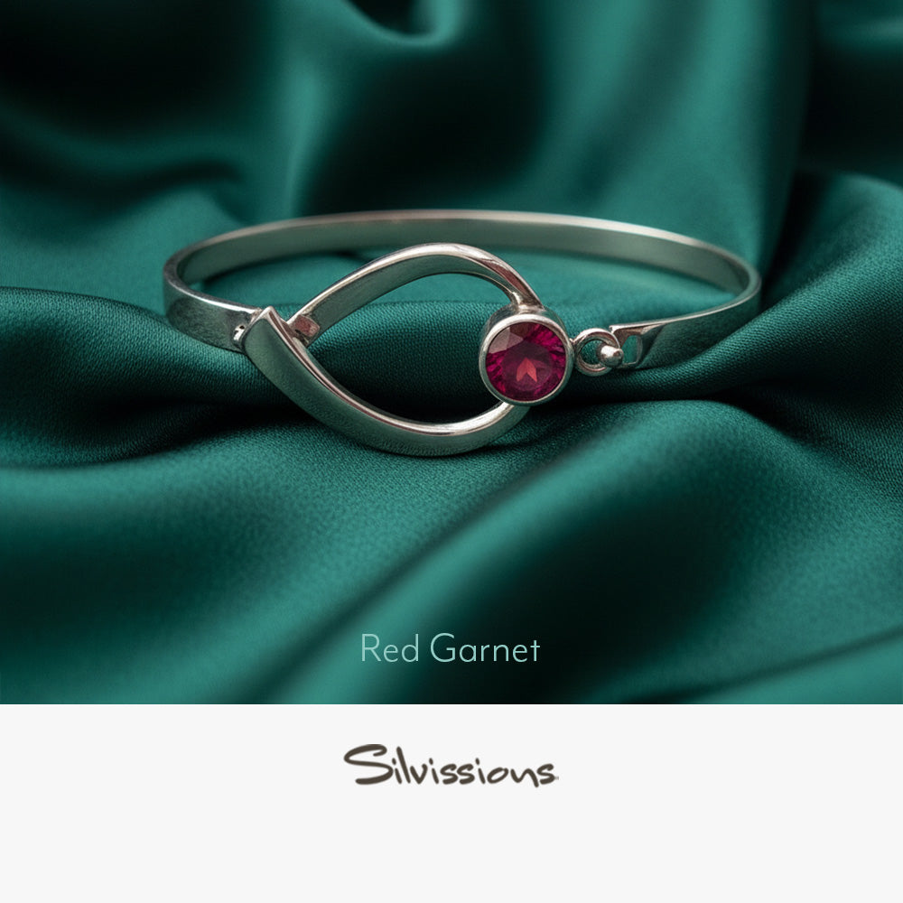 Silver ring with a red gemstone on a light green background, featuring the brand 'Silvissions'.
