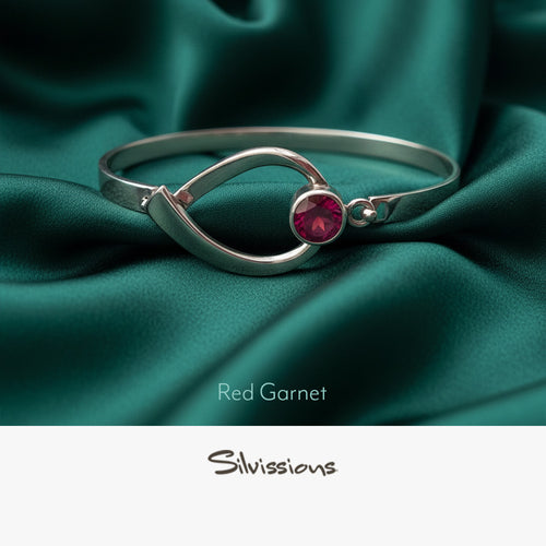 Silver ring with a red gemstone on a light green background, featuring the brand 'Silvissions'.