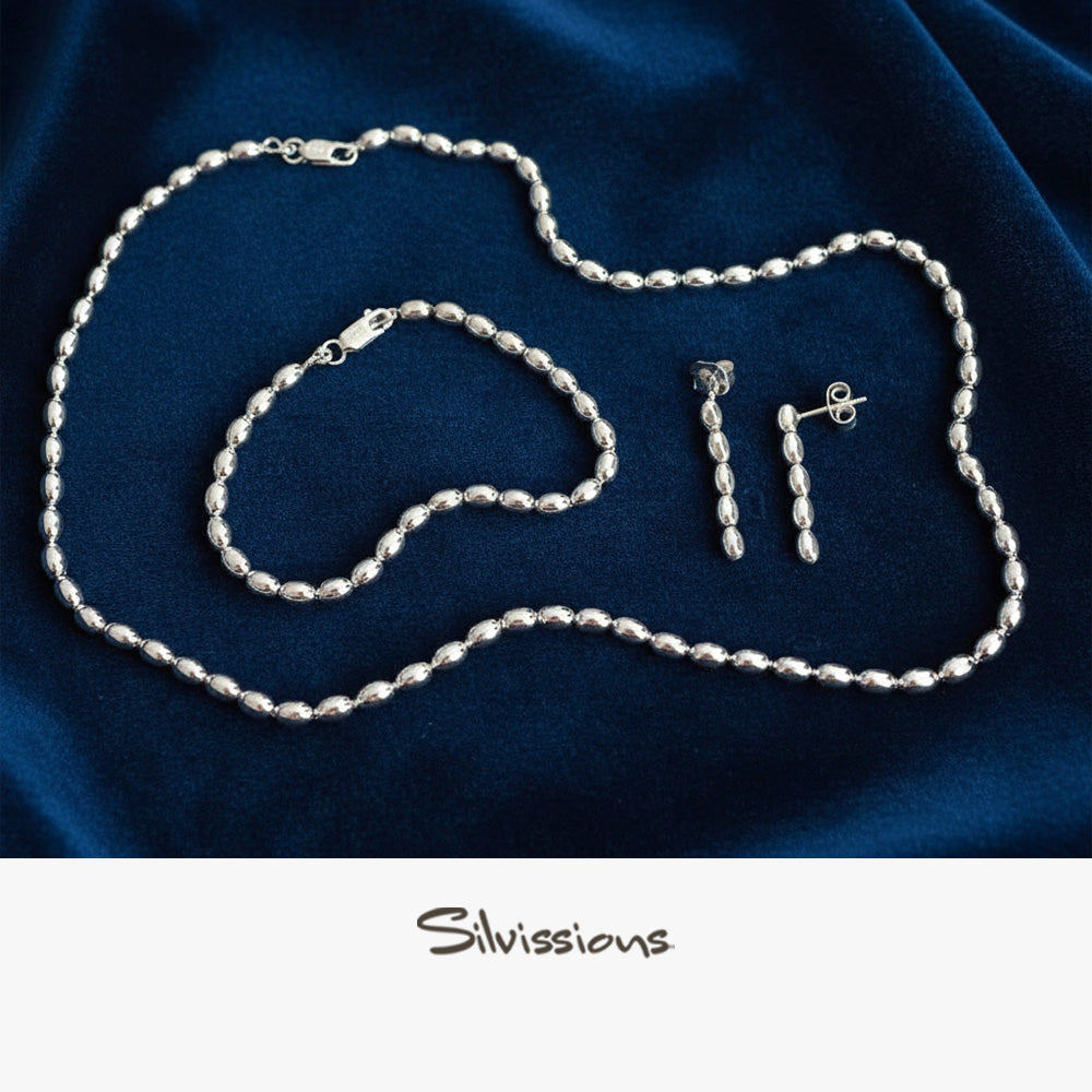 Silver necklace, bracelet and earrings on a blue fabric background with 'Silvissions' branding.