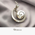 Silver brooch with pearl on a gray fabric background, branded 'Silvissions'.