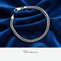 Silver braided bracelet on a blue fabric background with 'Silvissions' branding.