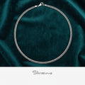 Silver necklace on a dark green fabric background with 'Silvissions' branding.