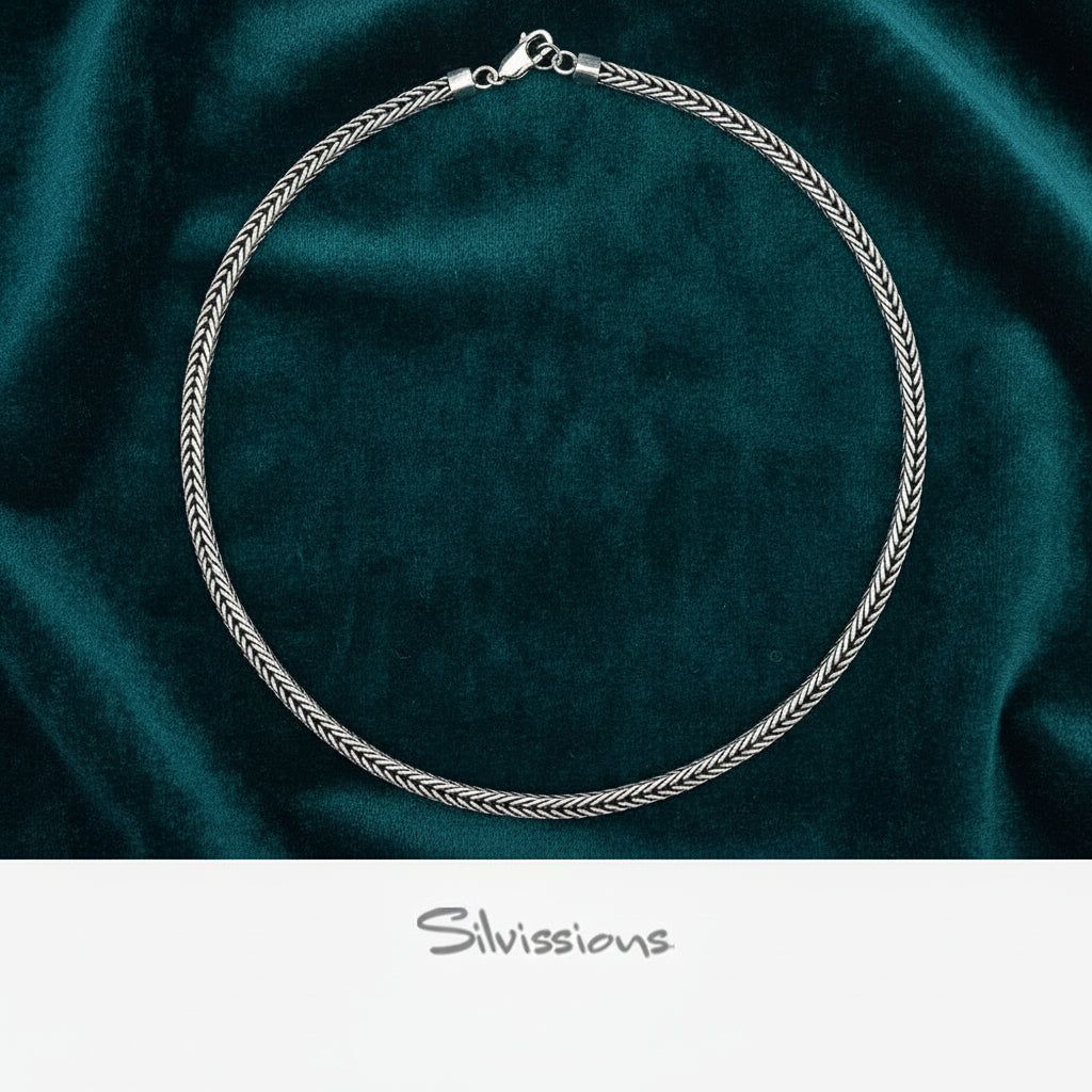 Silver necklace on a dark green fabric background with 'Silvissions' branding.