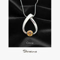 Silver pendant with a citrine stone on a black fabric background, featuring the brand 'Silvissions'.