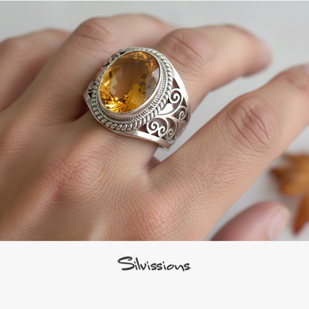 Silver ring with a yellow gemstone on a hand, branded 'Silvissions'.