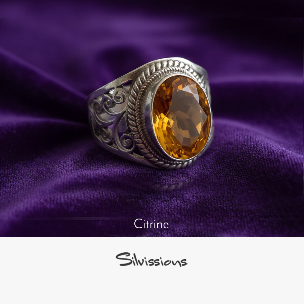 Silver ring with a citrine stone on purple fabric, featuring the brand 'Silvissions'.