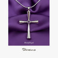Silver cross pendant with amethyst stone on purple fabric, featuring the brand 'Silvissions'.