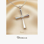 Silver cross pendant with pearl center on beige fabric, brand 'Silvissions' visible