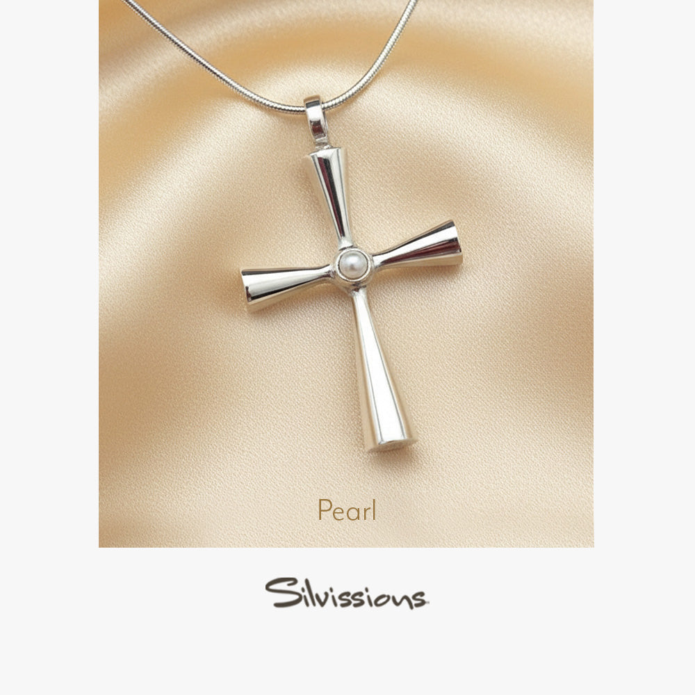 Silver cross pendant with pearl center on beige fabric, brand 'Silvissions' visible