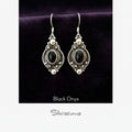 Silver earrings with black stones on a textured beige background, featuring the brand 'Silvissions'.