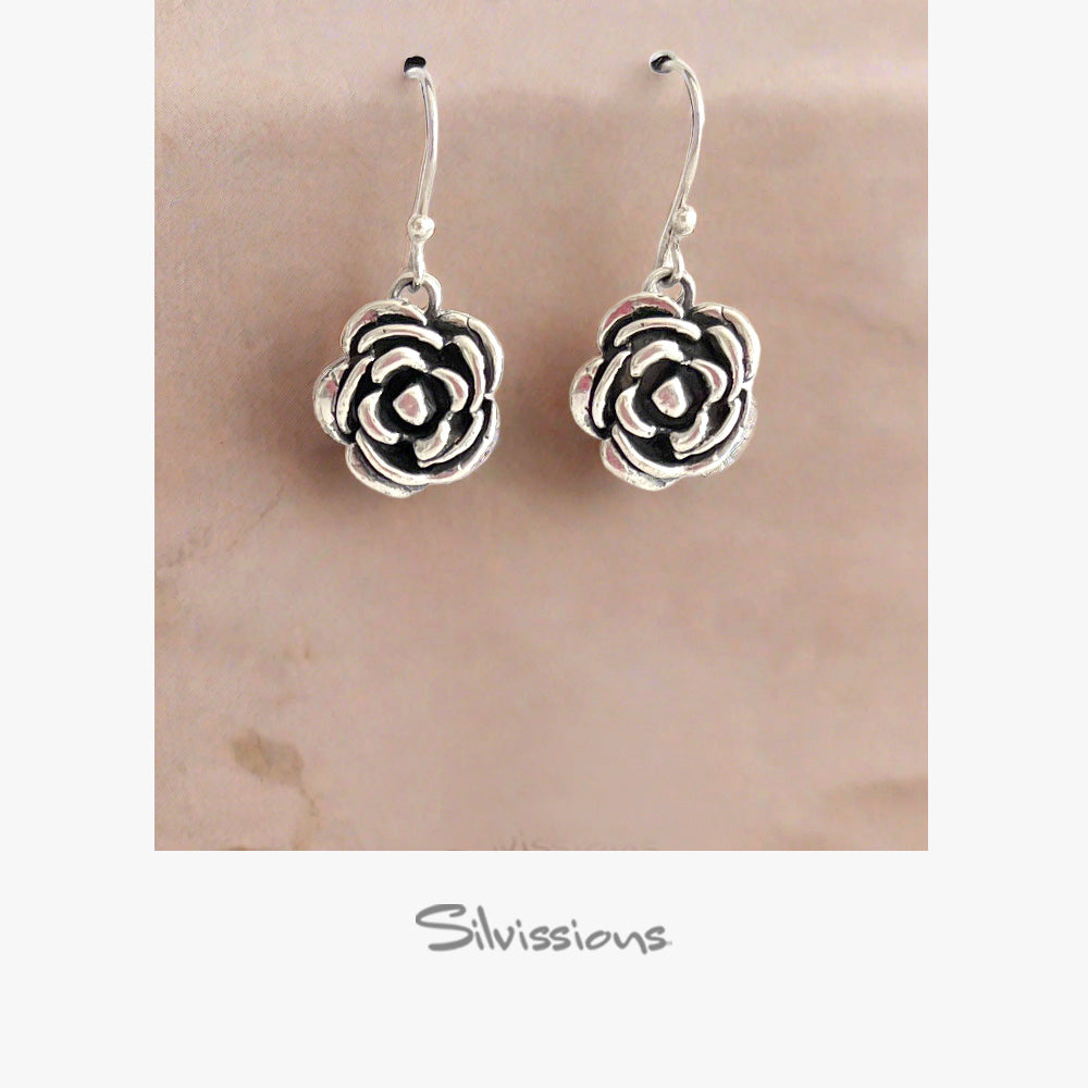 Silver rose-shaped earrings on a beige background with 'Silvissions' branding.