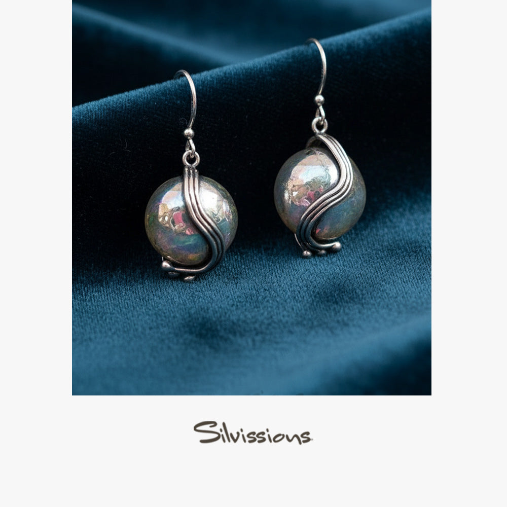 Sterling Silver dangle earrings on a blue fabric background, branded 'Silvissions'.