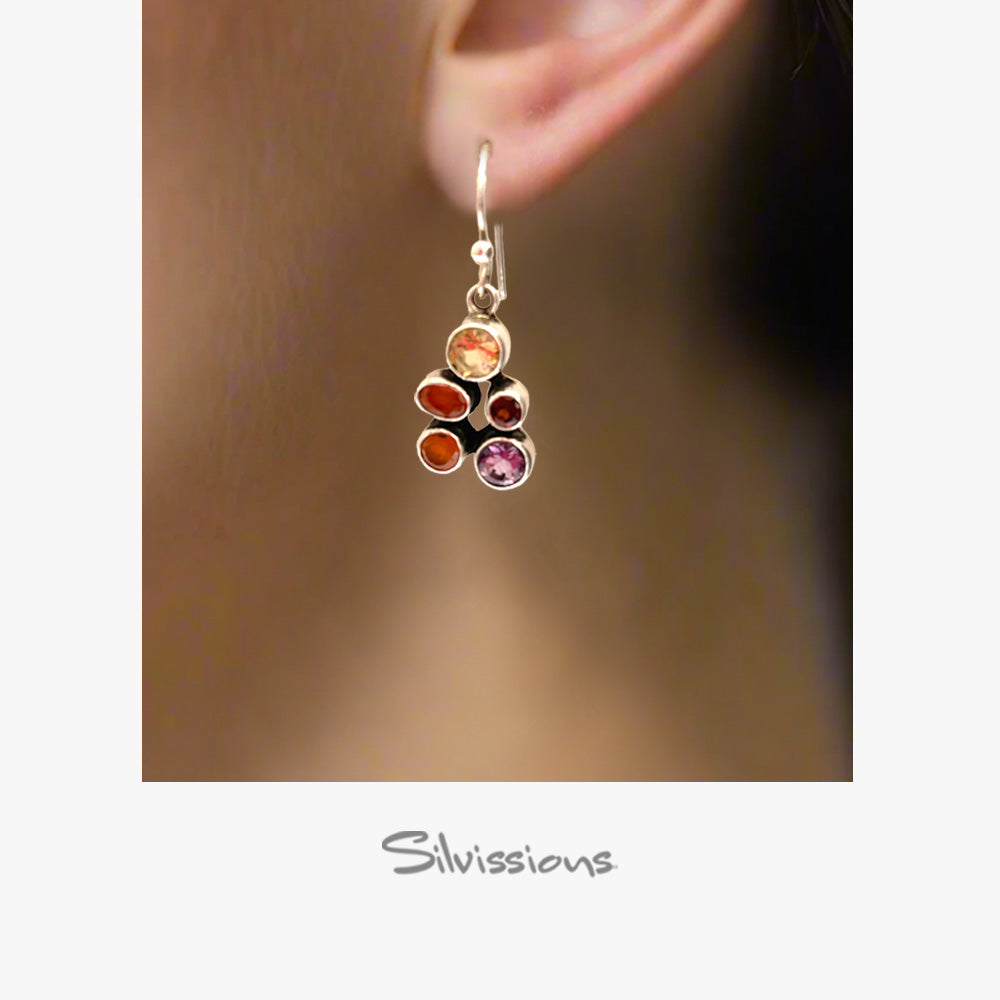 Earring with colored stones worn on an ear, brand 'Silvissions' visible