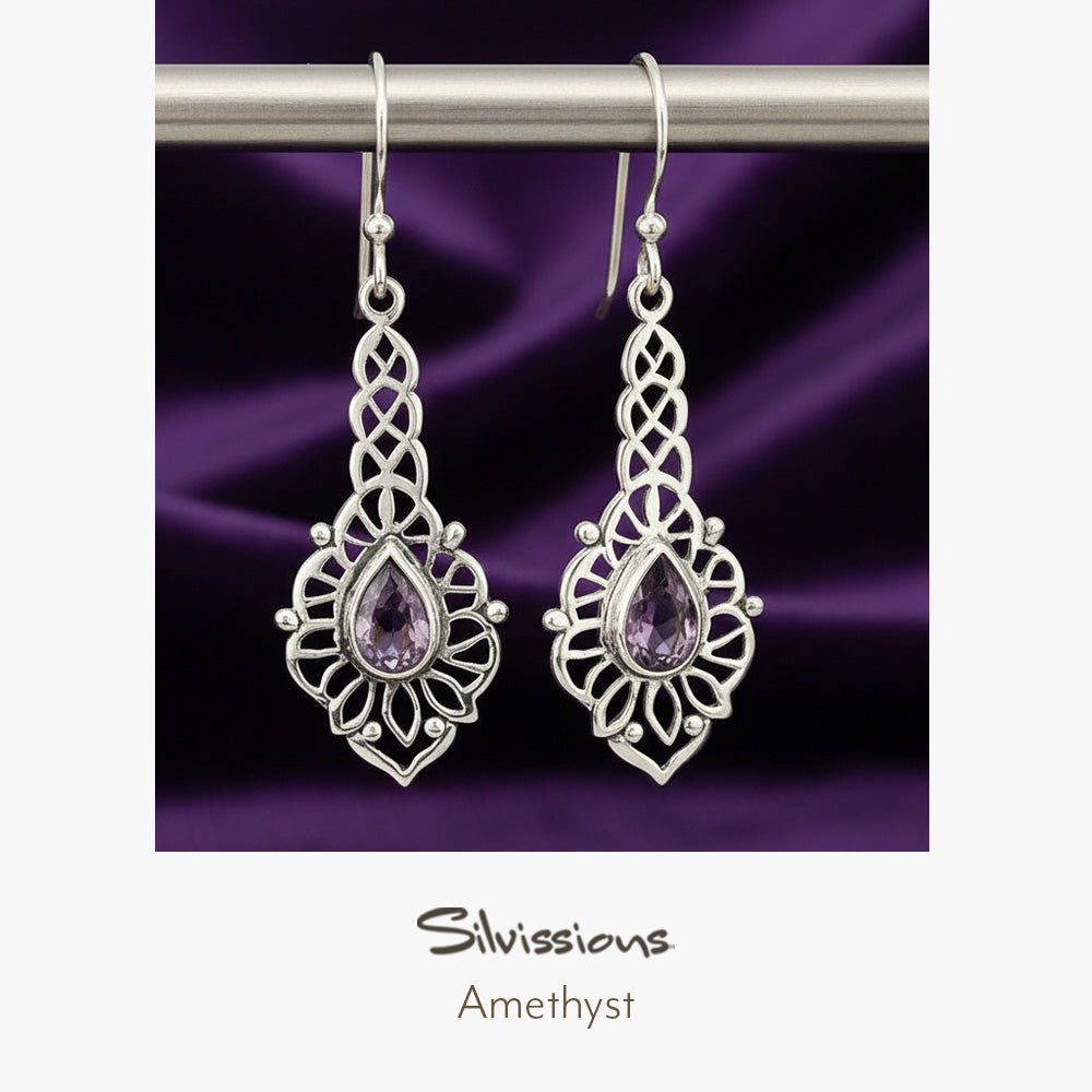 Silver earrings with purple gemstones on a purple background, branded 'Silviassions'.