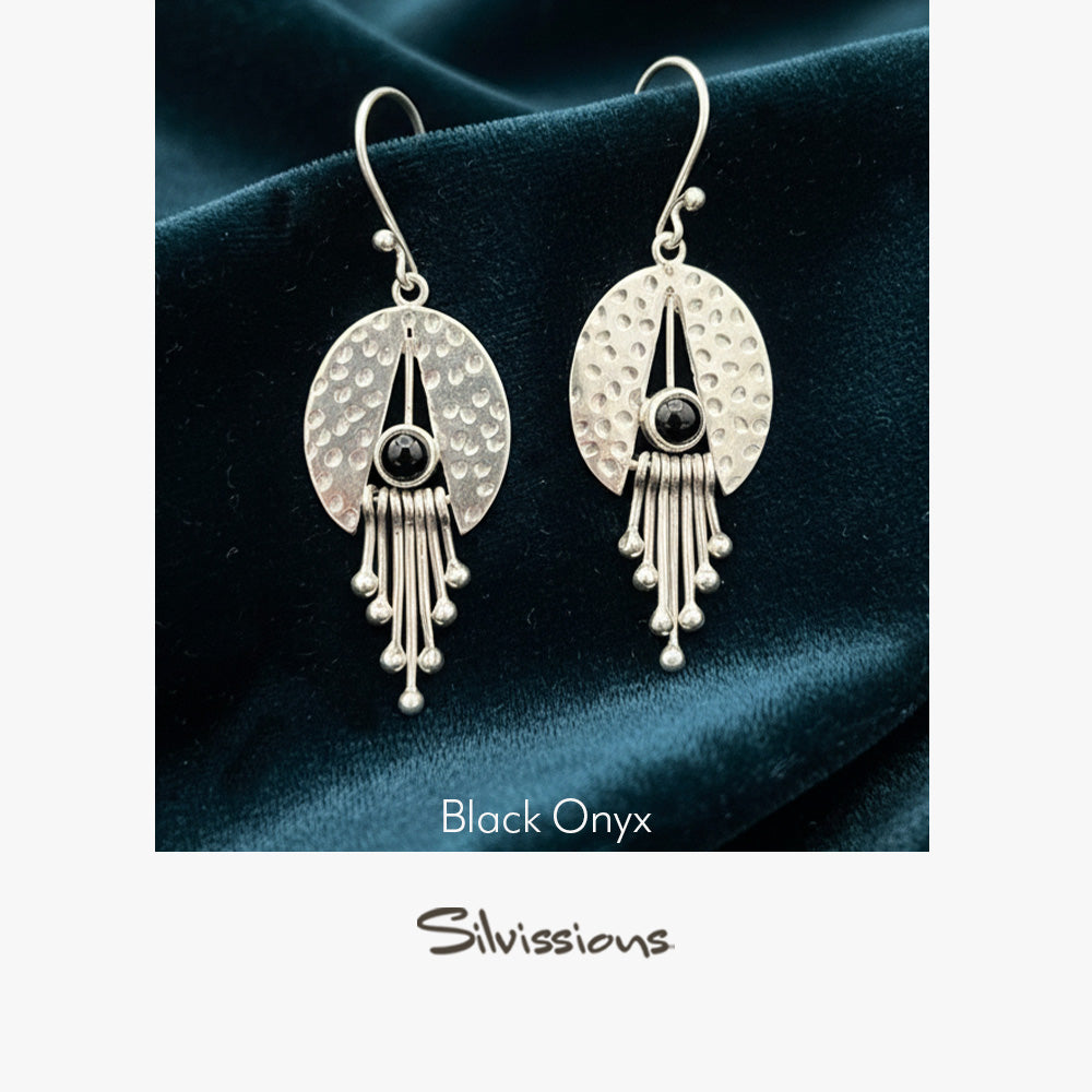 Silver earrings with black onyx stones on a dark fabric background, branded 'Silvissions'.