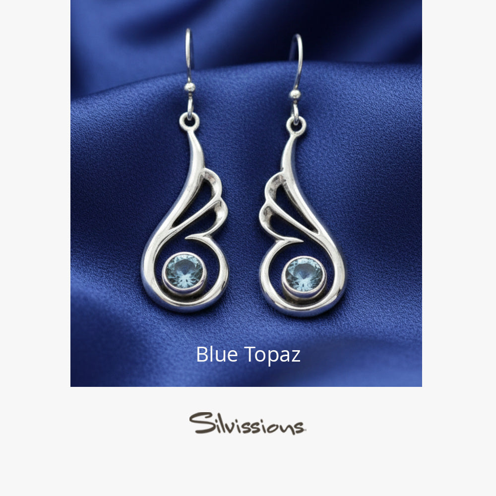 Silver earrings with blue gemstones on a blue fabric background, featuring the brand 'Silvissions'.
