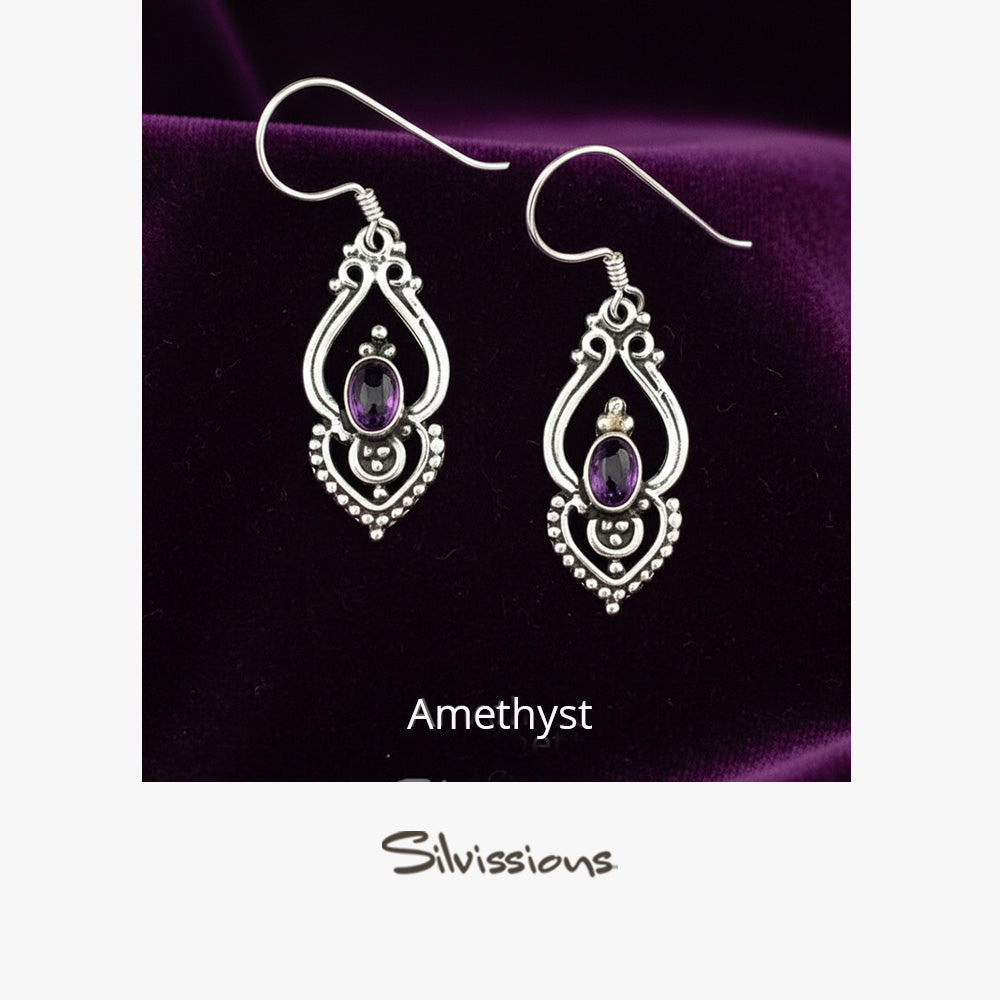 Pair of silver earrings with amethyst stones on a beige card, branded 'Silvissions'.