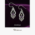 Pair of silver earrings with amethyst stones on a beige card, branded 'Silvissions'.