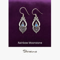 Silver earrings with rainbow moonstone stones on a gray background, branded 'Silvissions'.