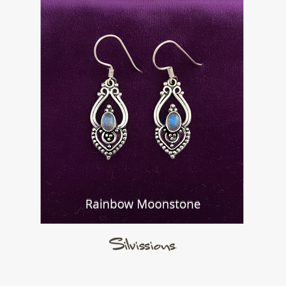 Silver earrings with rainbow moonstone stones on a gray background, branded 'Silvissions'.