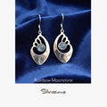 Silver earrings with rainbow moonstone stones on a blue fabric background