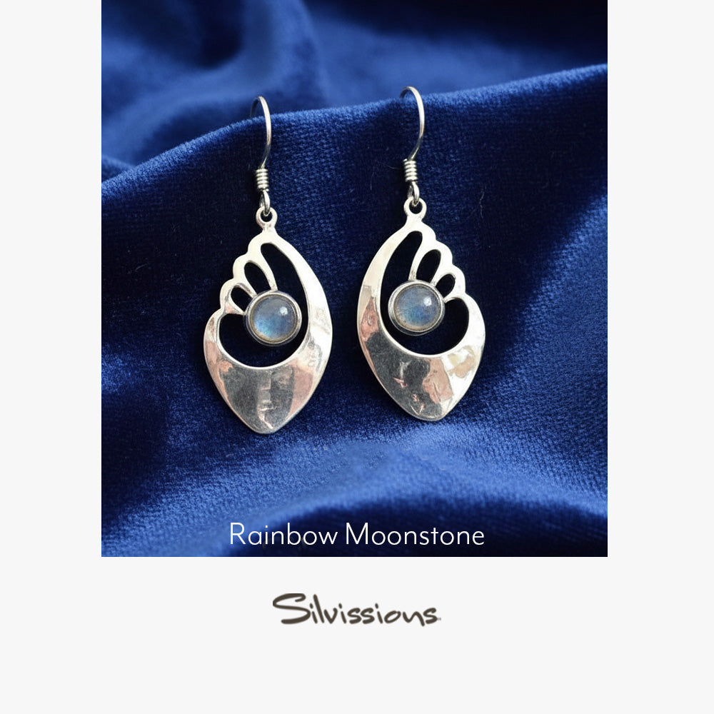 Silver earrings with rainbow moonstone stones on a blue fabric background