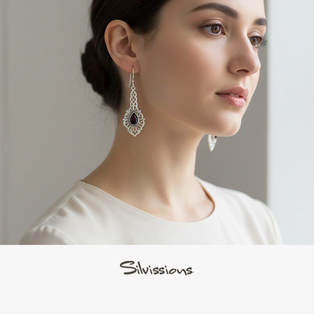 Silver earring with a red gemstone worn by a person, branded 'Silvissions'.