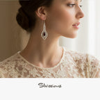 Woman wearing elegant earrings with a blurred background, featuring the brand 'Silvissions'.
