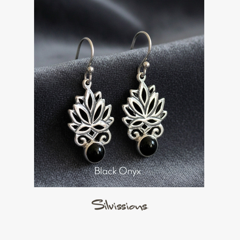 Silver lotus flower earrings with black onyx stones on a gray surface, branded 'Silvissions'.