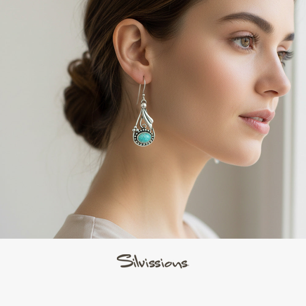 Woman wearing a silver earring with a turquoise stone, branded 'Silvassions'.