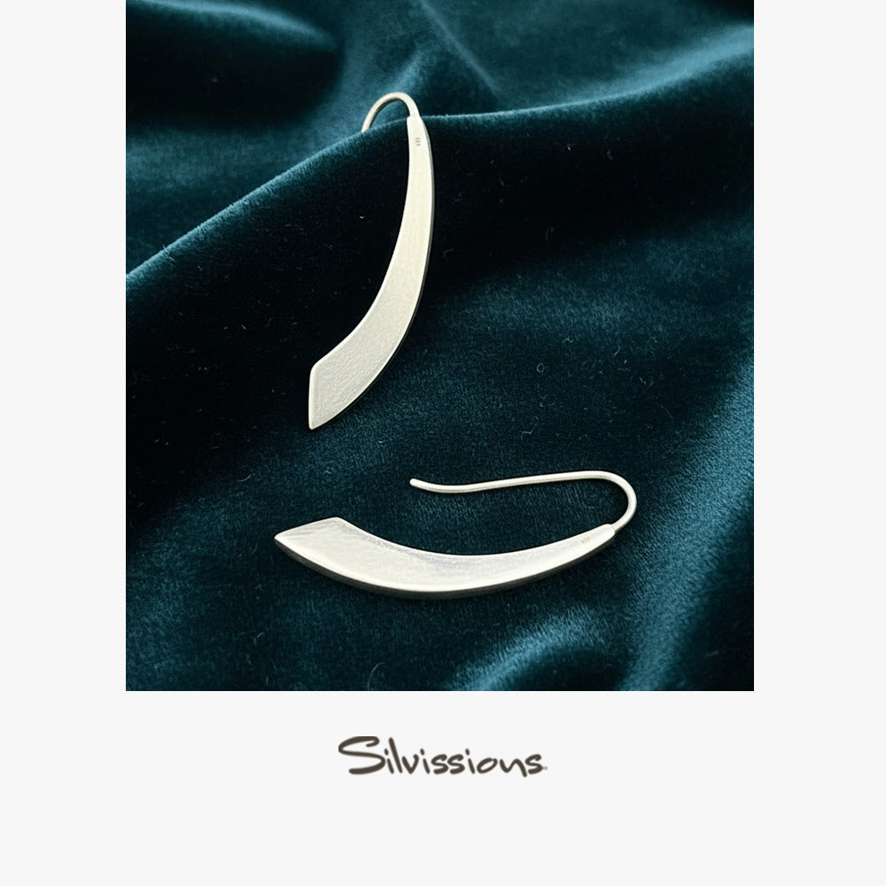Silver earrings on dark green fabric with 'Silvissions' branding.