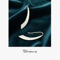Silver earrings on dark green fabric with 'Silvissions' branding.
