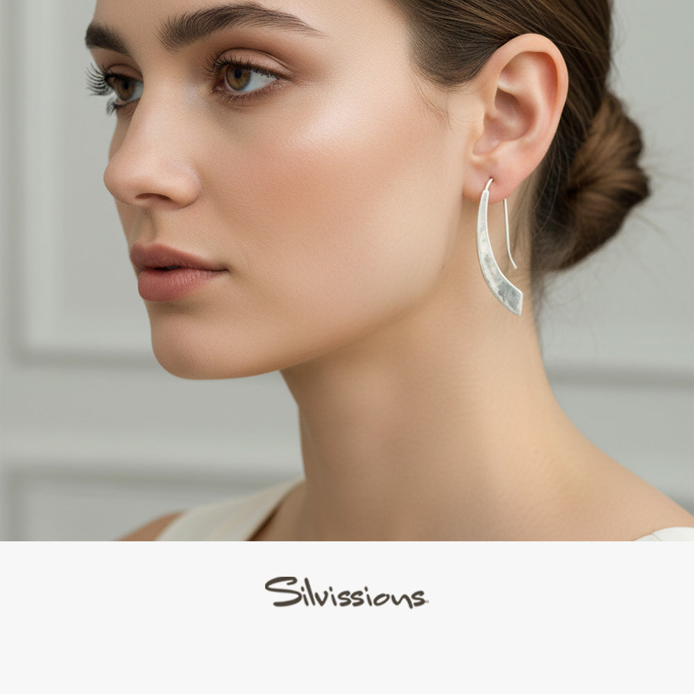 Close-up of a woman wearing silver hoop earrings with 'Silvissions' branding.