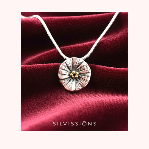 Silver necklace with a round pendant on a red satin background, featuring the brand 'Silvissions'.