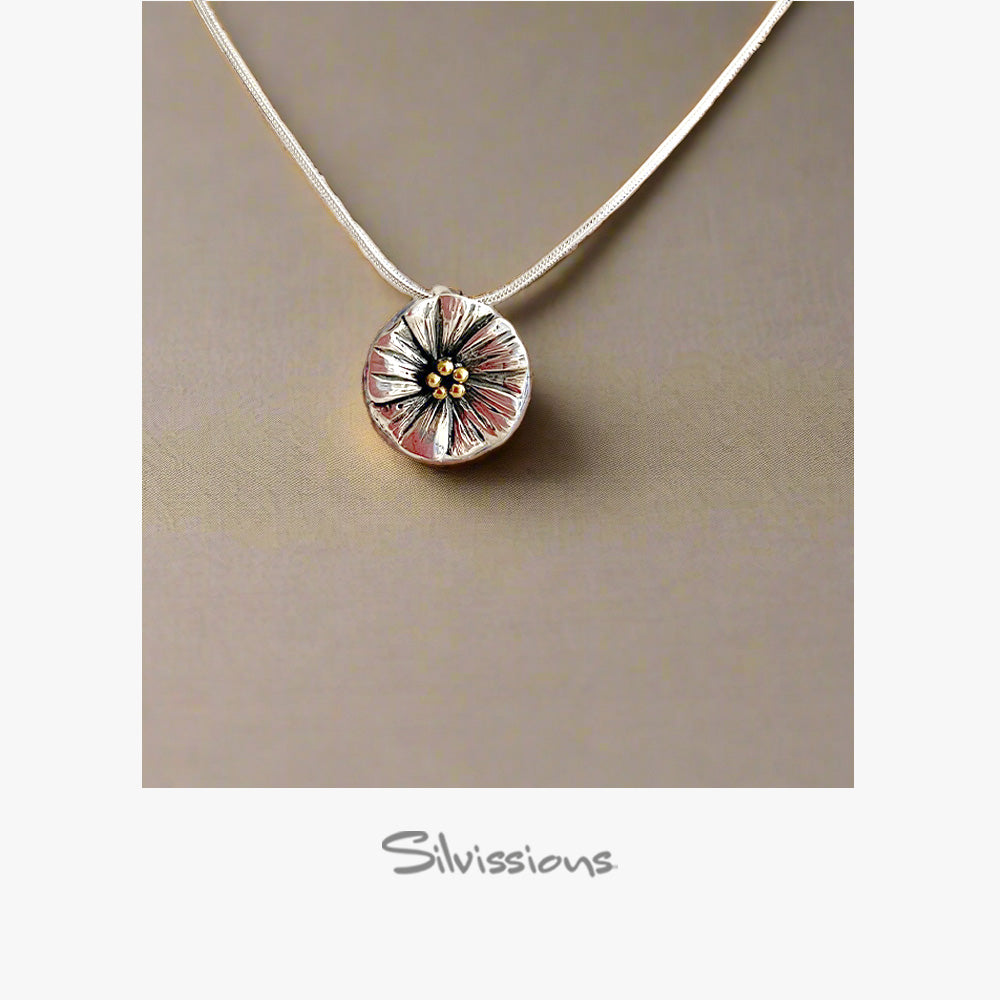 Silver necklace with a round flower pendant on a beige background, featuring the brand 'Silvissions'.