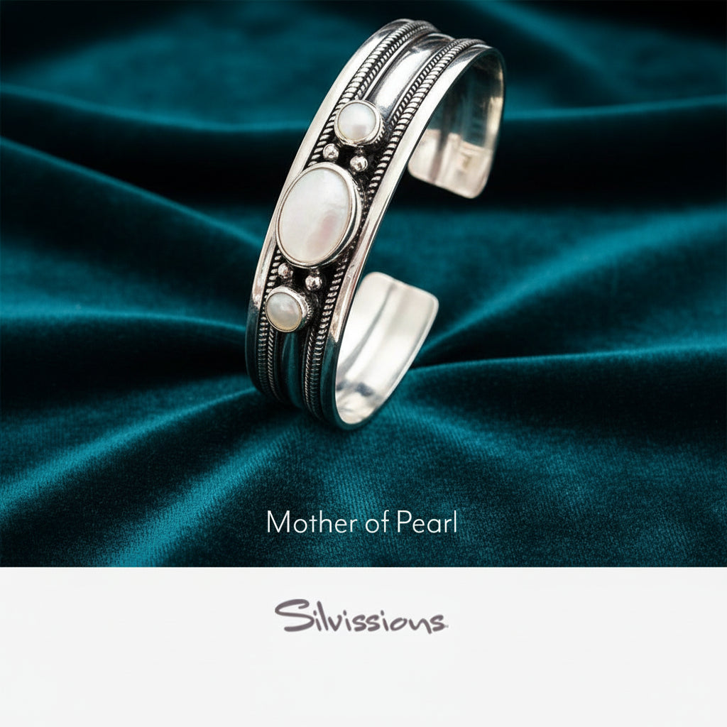 Silver bracelet with mother of pearl stones on a blurred background with tea set and flowers.