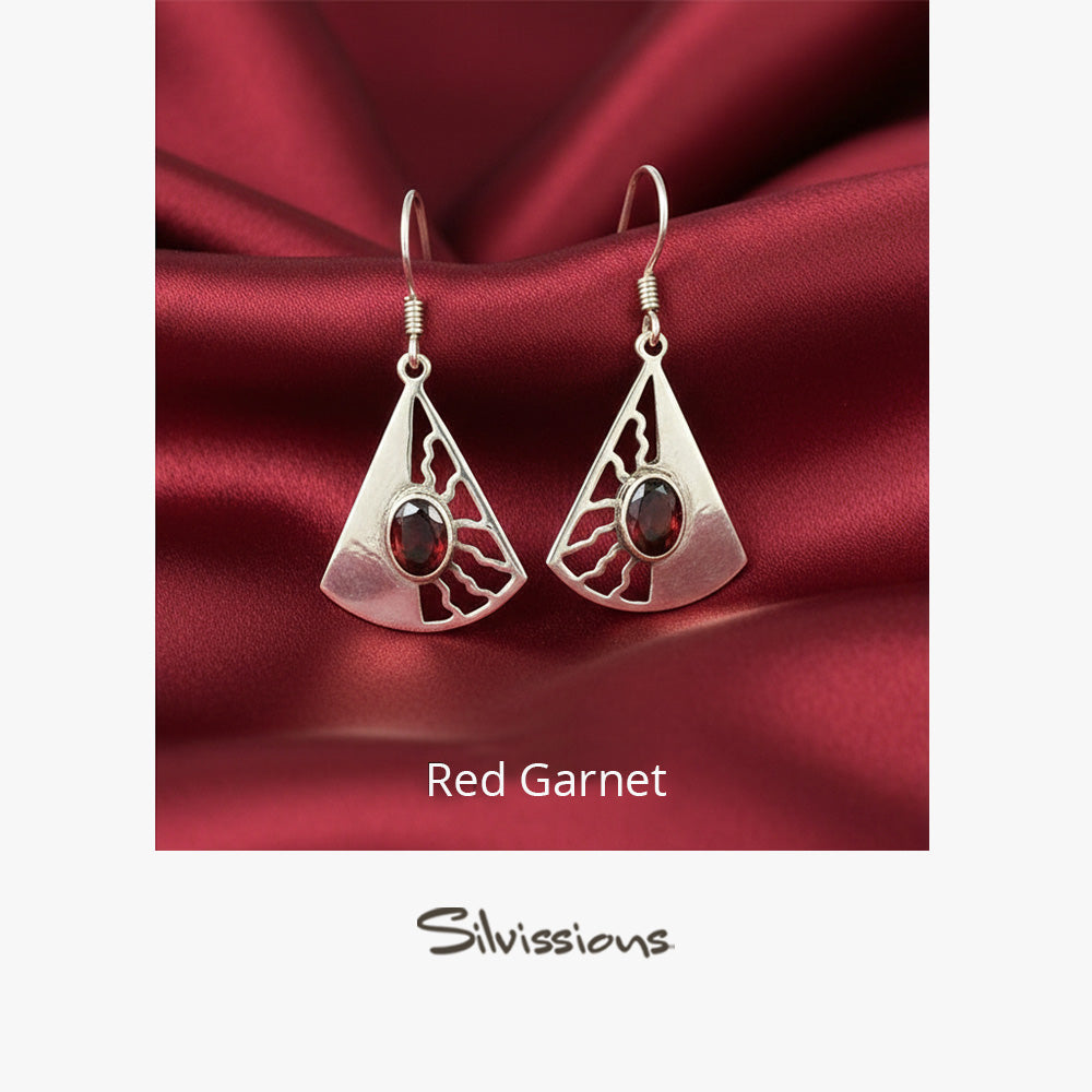 Silver earrings with red gemstones on a red satin background, branded 'Silvissions'.