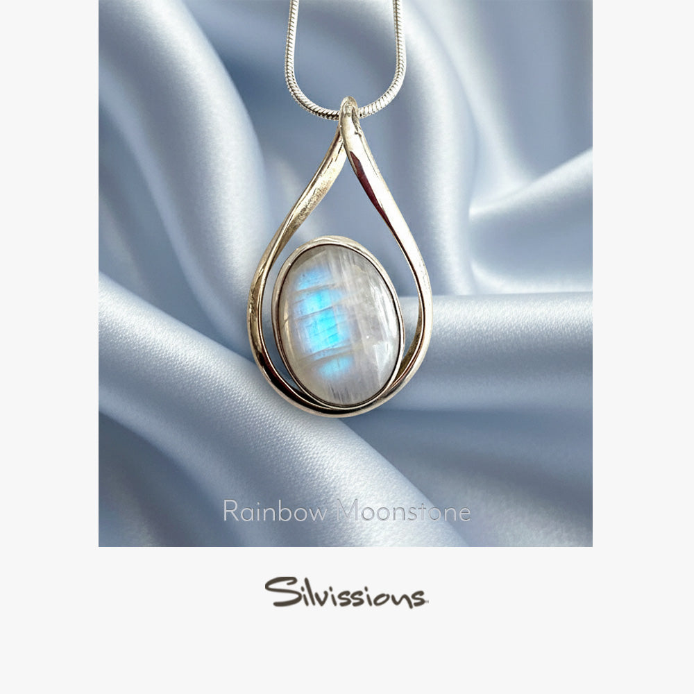Teardrop-shaped pendant with rainbow moonstone on a silver chain against a satin background, branded 'Silvassions'.