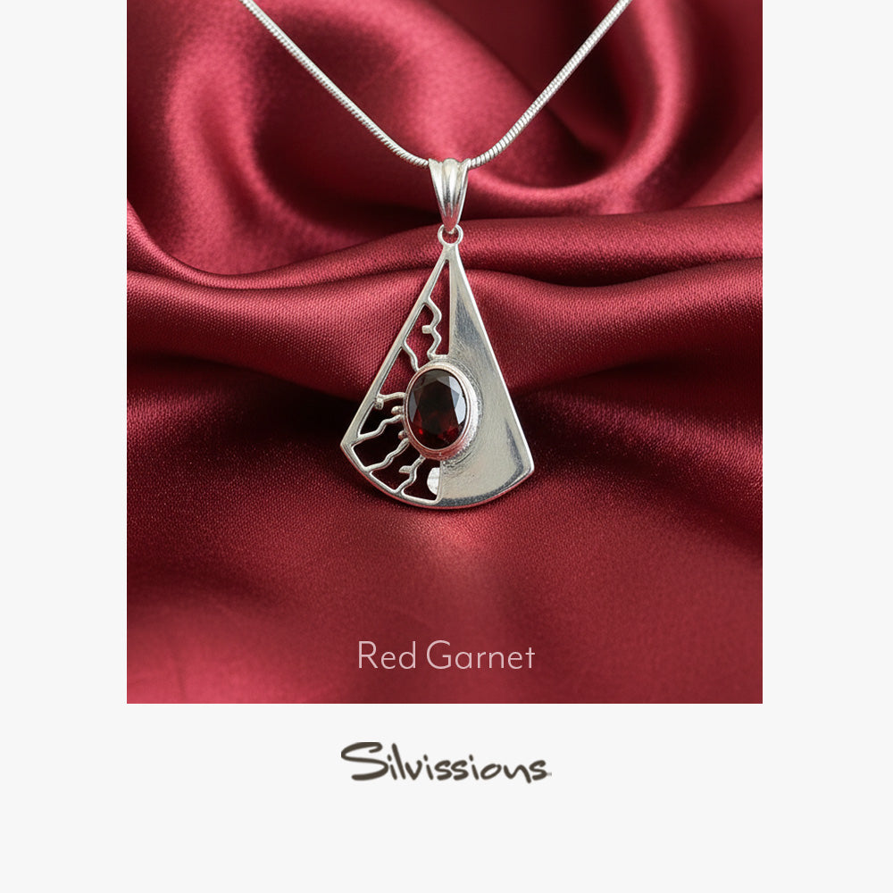 Silver pendant with red gemstone on a red satin background, featuring the brand 'Silvissions'.