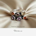 Silver ring with gemstones on a neutral background, featuring Silvissions Jewelry branding.