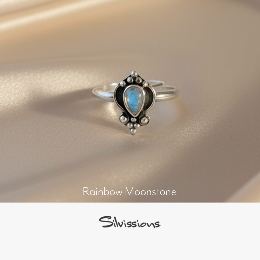Silver ring with an oval-shaped rainbow moonstone on a soft fabric background, featuring the brand 'Silvissions'.