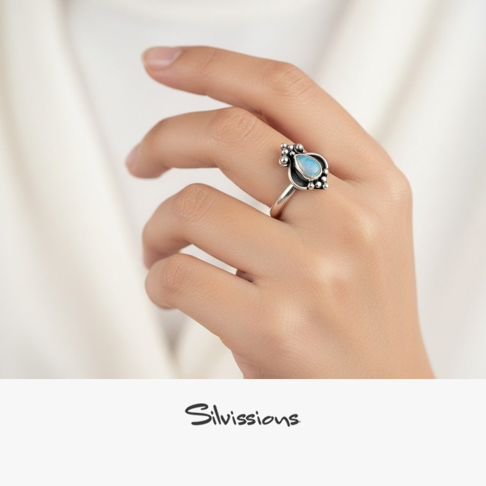 Silver ring with a blue gemstone held in a hand, branded 'Silvissions'.