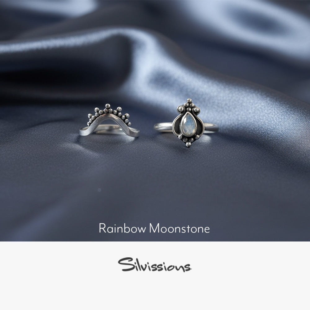 Two silver rings with gemstones on a dark fabric background, featuring the brand 'Silvissions'.
