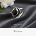 Silver ring with black onyx stone on gray fabric background, featuring the brand 'Silvissions'.