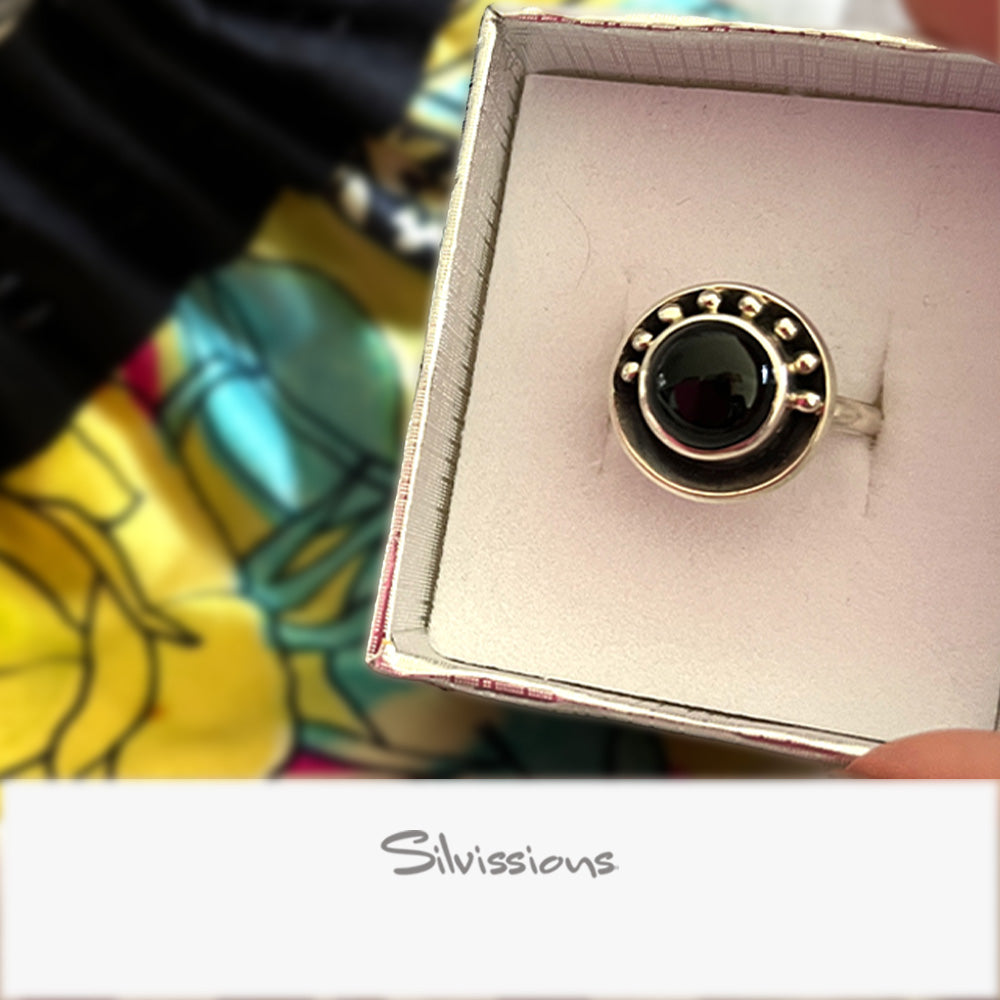 Sterling Silver ring with a black gemstone in a box labeled 'Silvissions' against a colorful background.