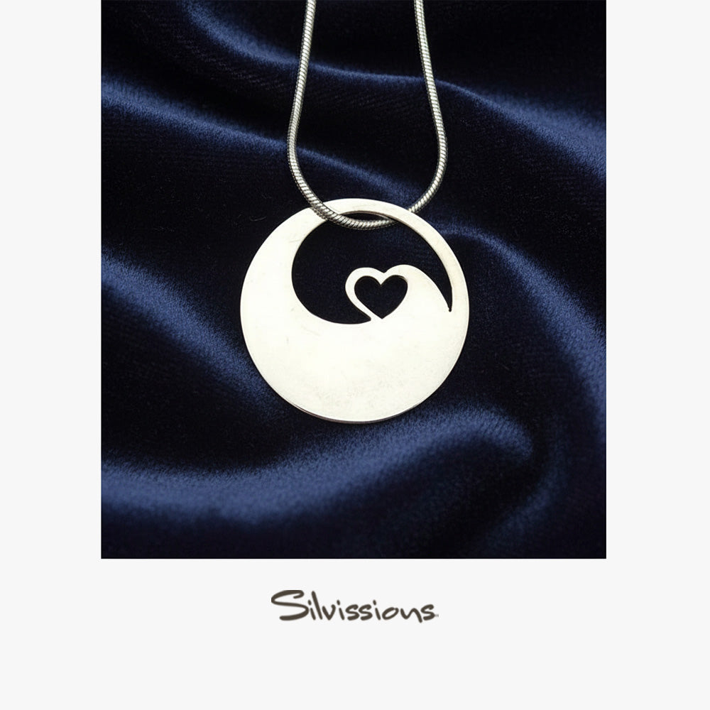 Silver necklace with a pendant featuring a heart design on a dark blue satin background, branded 'Silvissions'.