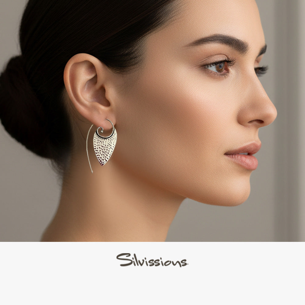 Close-up of a woman wearing a silver earring with 'Silvassions' branding.