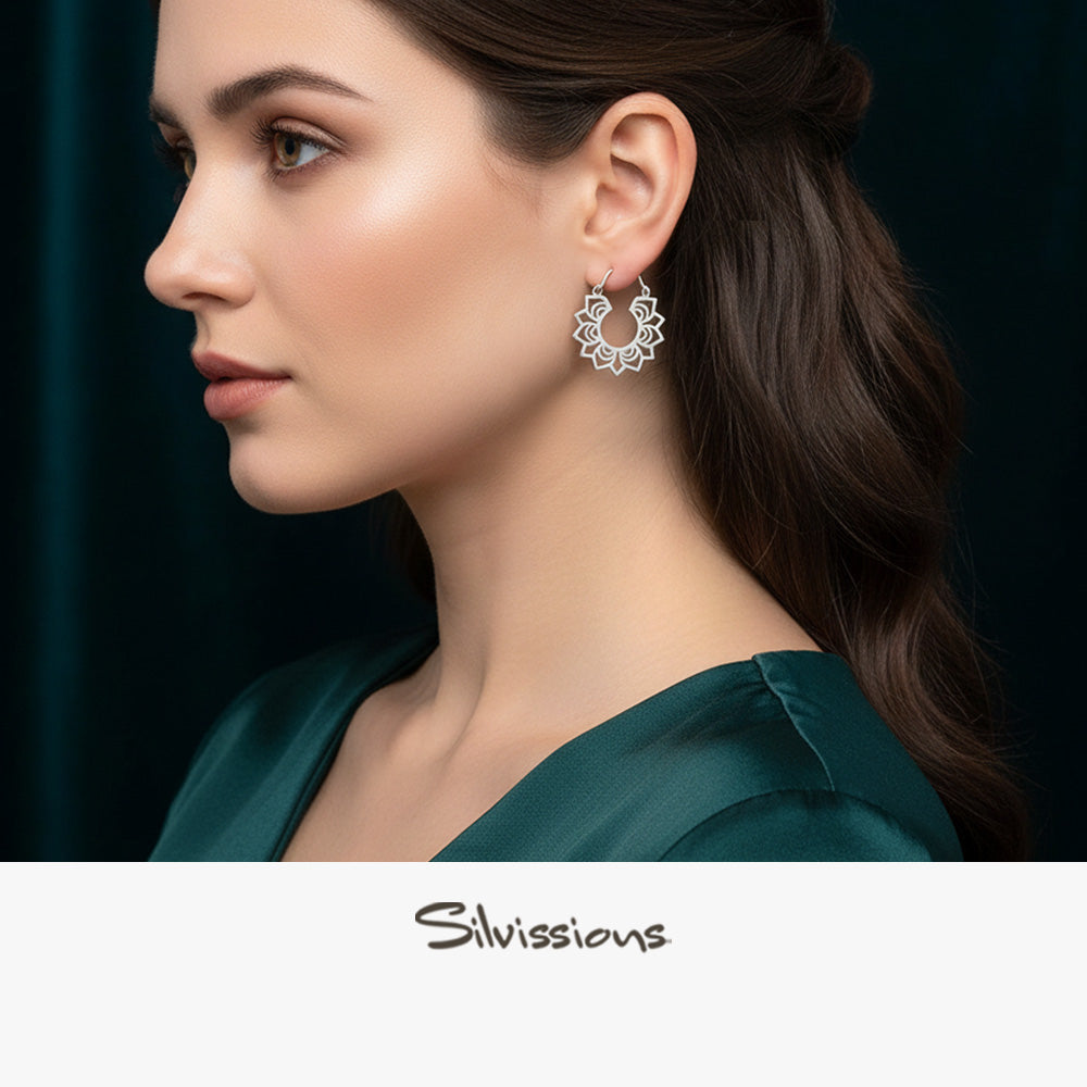 Woman wearing silver hoop earrings with a dark background, featuring the brand 'Silvissions'.