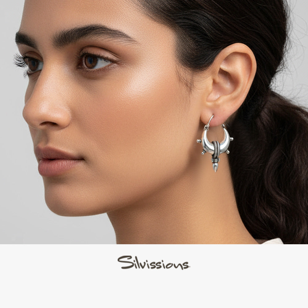 Woman wearing silver hoop earrings with a neutral background, featuring the brand 'Silvissions'.